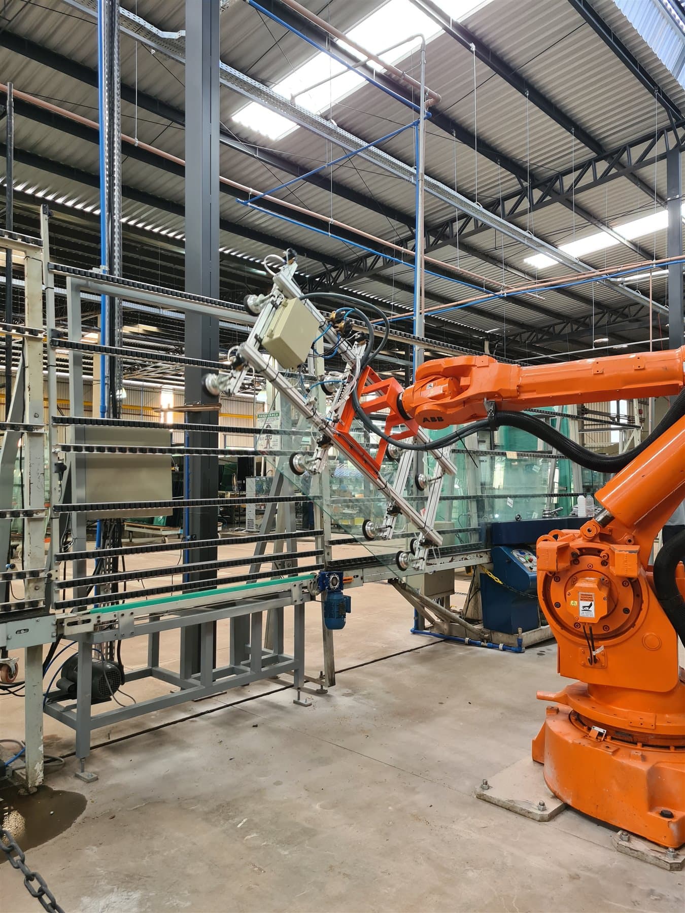 Robô industrial movimentando uma chapa de vidro na fábrica da Startemp